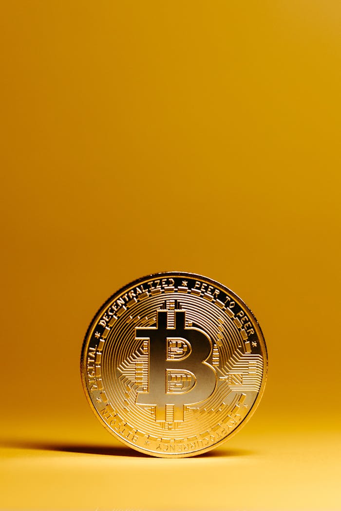 A golden Bitcoin coin stands out against a vivid yellow background, representing digital currency and financial technology.
