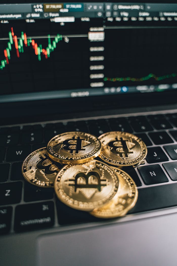 Golden bitcoins on a laptop keyboard with a trading chart in the background, symbolizing digital currency and finance.